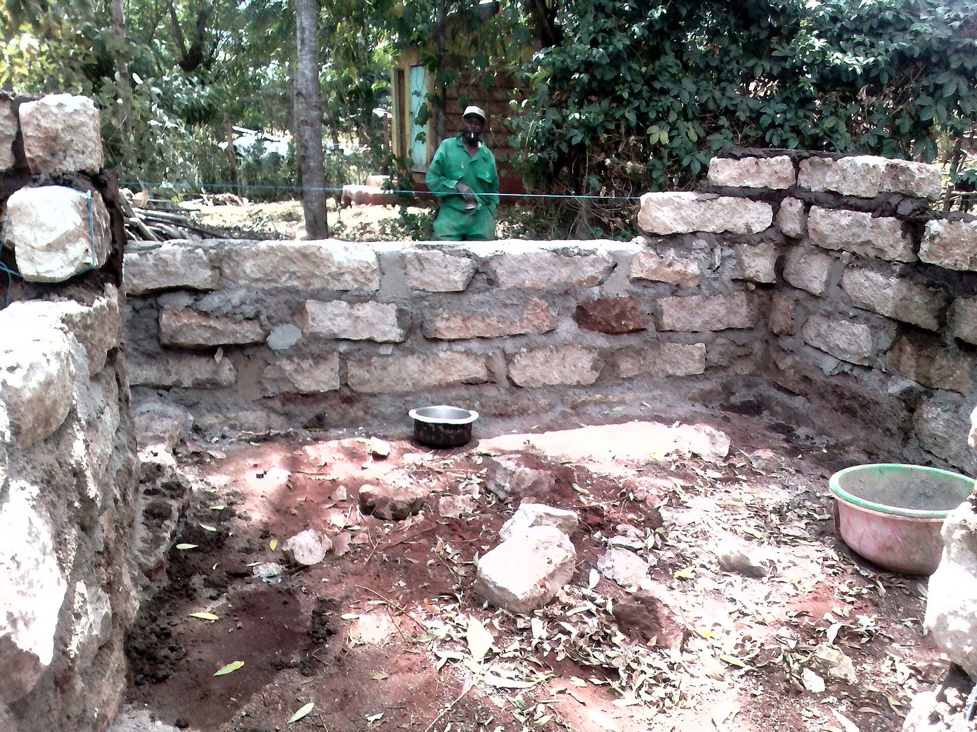 Mason laying stone blocks on a wall in Kenya